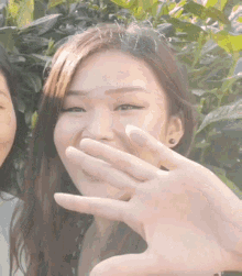 a woman covering her mouth with her hand while another woman looks on .