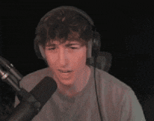 a man wearing headphones is sitting in front of a microphone and making a funny face .