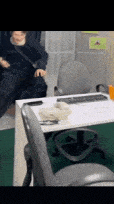a person is sitting at a desk with a keyboard and a telephone on it .