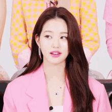 a woman in a pink jacket sits on a black couch