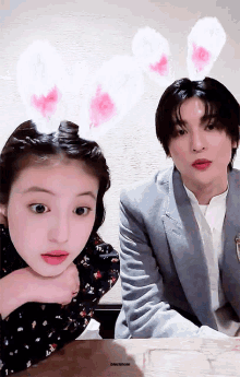 a girl wearing bunny ears sits next to a man wearing a suit