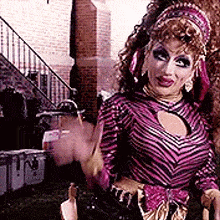 a woman in a zebra print dress is waving her hand in front of a brick building .