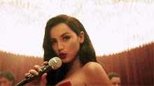 a woman in a red dress is singing into a microphone in a room .