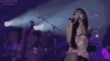 a woman in a pink dress singing into a microphone on a stage