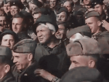 a large group of men in military uniforms are standing in a crowd of people .