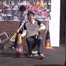 a man is sitting in a chair holding a traffic cone while a woman stands behind him .