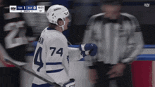 a hockey player with the number 74 on his jersey stands on the ice