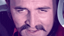 a man with a mustache is smiling and looking at the camera