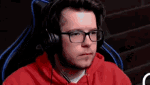 a man wearing glasses and headphones is sitting in a chair and looking at the camera .