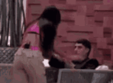 a woman in a pink bikini is sitting next to a man on a couch .