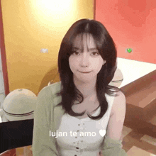 a woman in a white tank top and green cardigan is sitting in a room with a red wall .