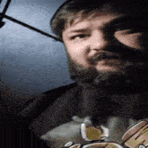 a man with a beard is wearing a black shirt with a picture of a cat on it