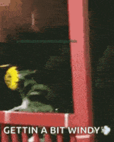 a yellow flower with a face on it is sitting on top of a red fence .