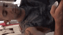 a man is laying on his back with his eyes closed and his hand on his face .