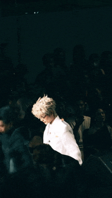 a man in a white jacket stands in front of a crowd