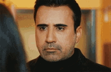 a man with a beard and mustache is looking at another man .