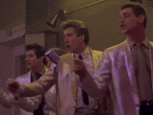 a group of men are singing into microphones in a dimly lit room