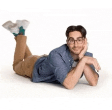 a man is laying on his stomach on the floor with his legs crossed and his head resting on his hand .