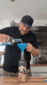 a man is pouring liquid into a bottle with a funnel