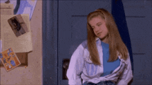 a woman is standing in front of a blue door with her shirt up .