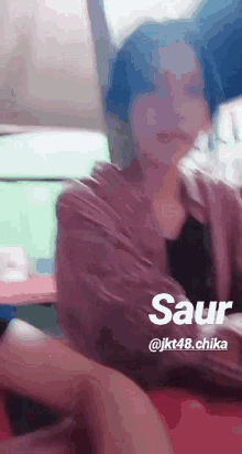 a woman is sitting on a bed with the name saur written on the bottom