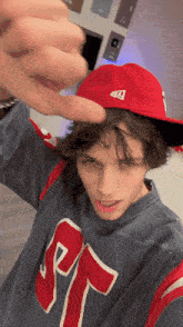 a young man wearing a red hat and a gray shirt with the letter r on it