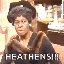 a woman in a fur coat and hat is sitting on a couch and says `` heathens !!! '' .
