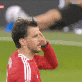 a man in a red and white adidas jersey holds his head