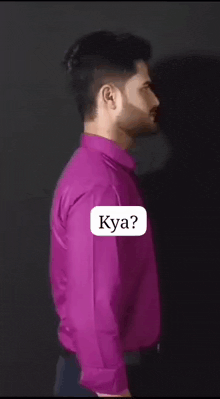 a man in a purple shirt is standing in front of a black background with a sticker that says kya .
