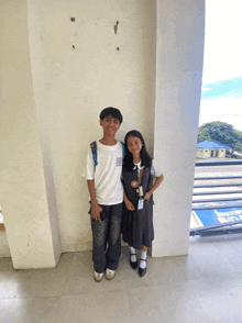 a boy and a girl standing next to each other in a hallway with a sign that says " exit " on it