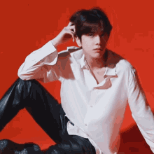a man in a white shirt and black pants is sitting on the floor