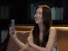 a woman is sitting on a couch holding a cell phone