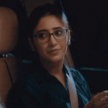 a woman wearing glasses and a blue shirt is smiling