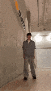 a man in a grey jacket stands in a hallway in front of a wall that has the word jellyfish on it
