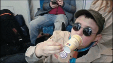 a boy scout wearing sunglasses and a hat drinks from a cup that says 100 % recyclable