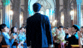 a man in a suit is standing in front of a crowd of people at a church .