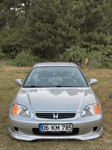 a silver honda car has a license plate that says 06 km 785