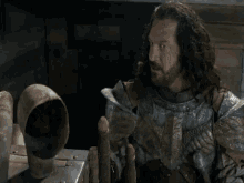 a man with long hair and a beard is holding an axe .