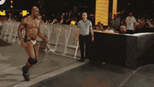 a referee stands behind a man in a wrestling trunks