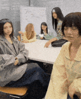 a group of girls are sitting around a table with a white board that says dior on it