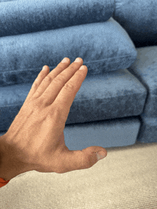 a man 's hand is reaching out to touch a blue couch