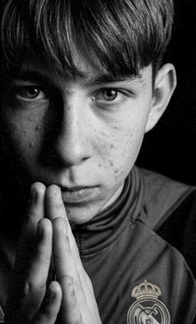 a black and white photo of a young man wearing a real madrid jersey
