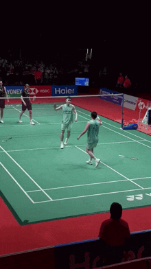 a badminton game is being played on a court with a haier banner