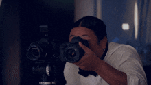 a man taking a picture with two cameras one of which says nikon