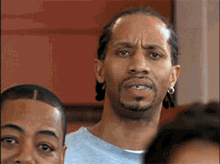 a man with a beard and earrings is making a funny face in a crowd of people .