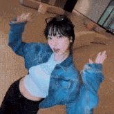 a woman wearing a denim jacket and a white t-shirt is standing in a hallway with her arms outstretched