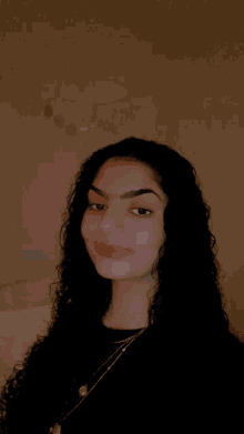 a young woman with curly hair is smiling for the camera .
