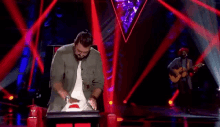 a man is dancing on a stage while another man plays a guitar in the background .