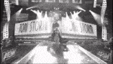 a black and white photo of a wrestler in front of a aew sign