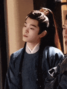 a young man with long hair is wearing a ponytail and a traditional costume .